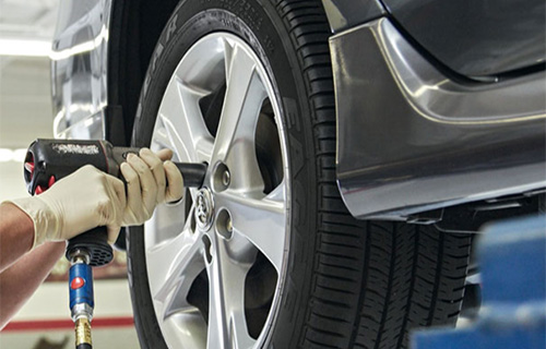 Gloved mechanic hands hold a tool for tire replacement service