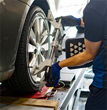 A mechanic checks alignment on a wheel in Pompano Beach after a customer uses these coupons and discounts