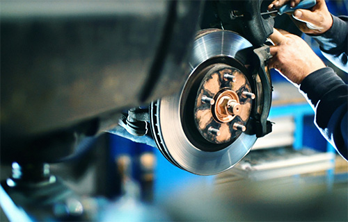 Mechanic hands adjust brakes during brake automotive services in Pompano Beach