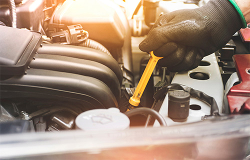Gloved mechanic hands work on the hood of a car during auto repair