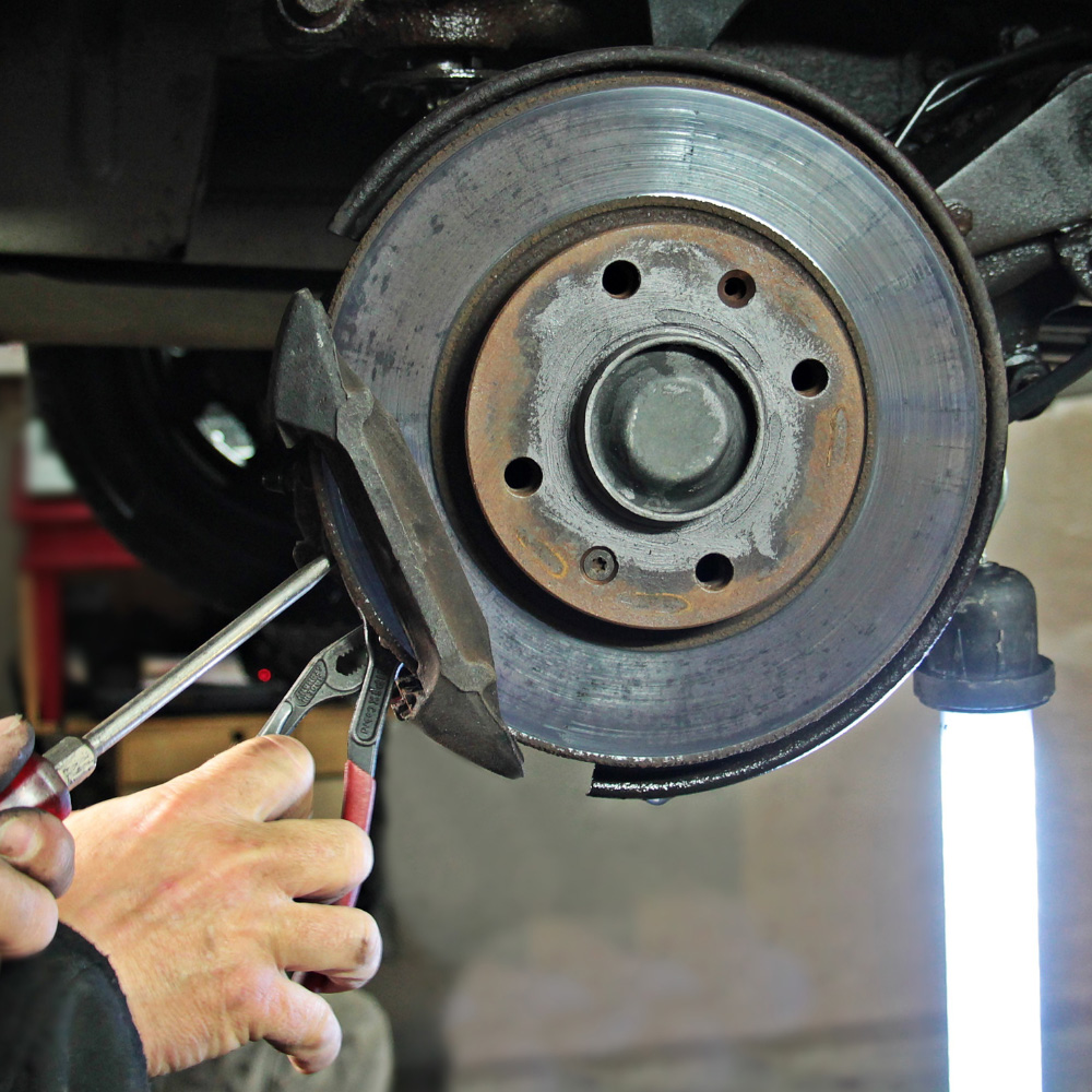 Hands working on a brake disc during brake repair in Pompano Beach