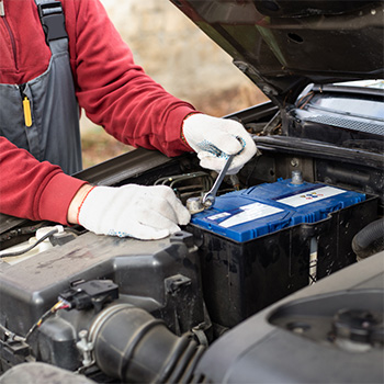 Mechanic adjusts the secure bolts holding a car battery in place after battery replacement