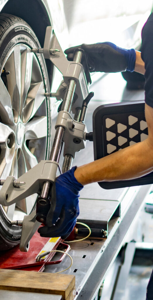 Mechanic aligns a tire for wheel alignments in Pompano Beach