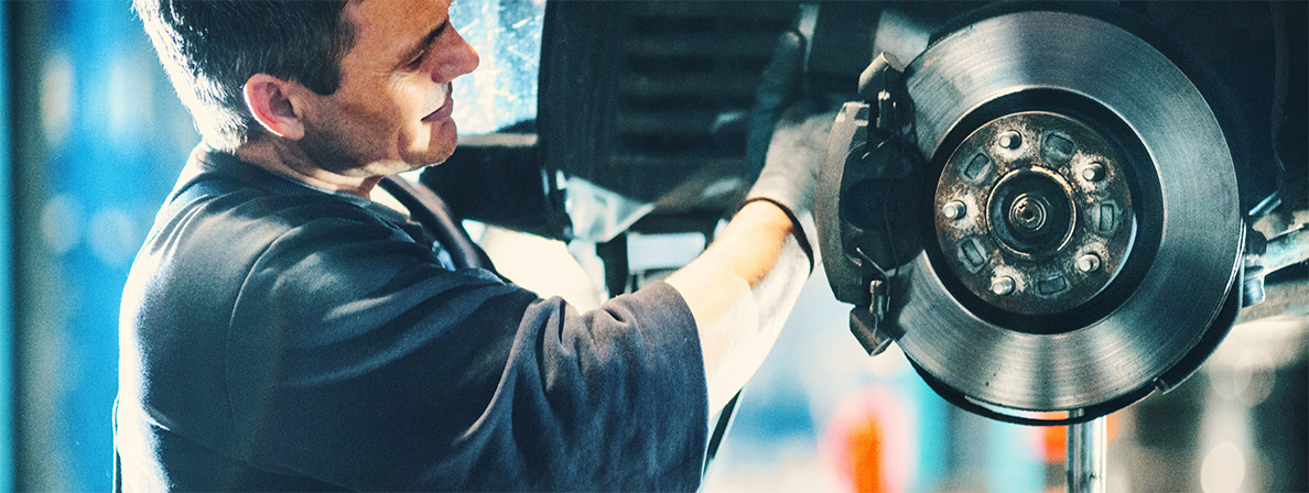 A mechanic smiles while working on brake service in Pompano Beach
